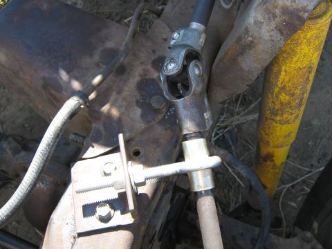 1972 Ford F-250 - Close-up of a steering shaft U-joint (universal joint) connecting an upper black steering column shaft to a lower shaft with a gold-colored…