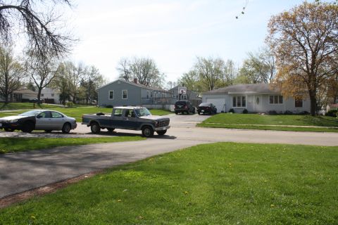 1985 Ford F-350 - A blue and grey pickup truck is seen driving down a residential street with other vehicles present.