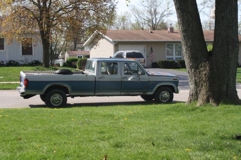 1985 Ford F-350 - A blue and gray crew cab pickup truck is parked on the side of a street in front of a house.