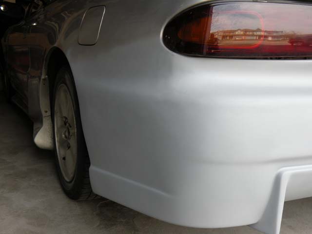 1994 Mazda MX-6 rear quarter panel, taillight, and wheel. The car is silver and appears to be in a garage
