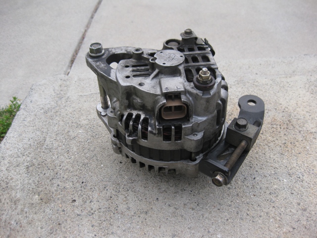Car alternator with mounting bracket, resting on concrete
