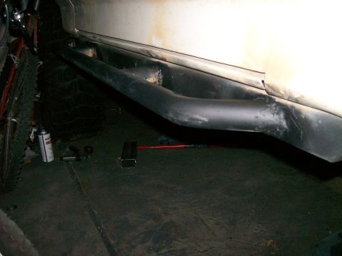 1989 Ford Bronco - A close-up side view of a vehicle's lower body, showing aftermarket side steps and a tire.