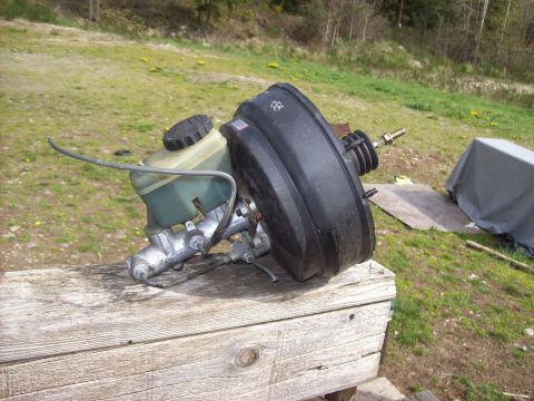 1985 Toyota Pickup/SR5 - A brake booster and master cylinder assembly is shown resting on weathered wooden planks.