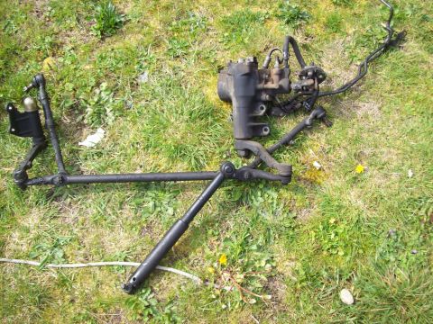 1985 Toyota Pickup/SR5 - Steering rack and tie rod assembly, likely for a truck, lying on a grassy surface.