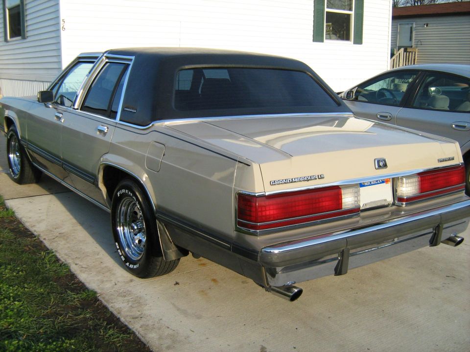 Rear view of a tan 1988 Mercury Grand Marquis with a black vinyl top parked on a driveway