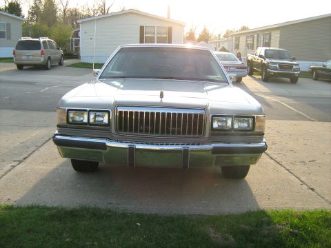 1988 Mercury Grand Marquis - Front view of a silver 1988 Mercury Grand Marquis parked in a driveway with other vehicles present.