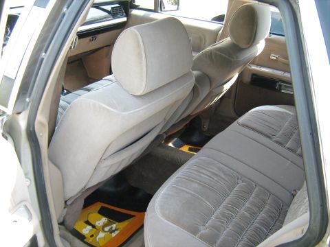 1988 Mercury Grand Marquis - The interior of a car features beige velour seats and distinctive Homer Simpson floor mats.