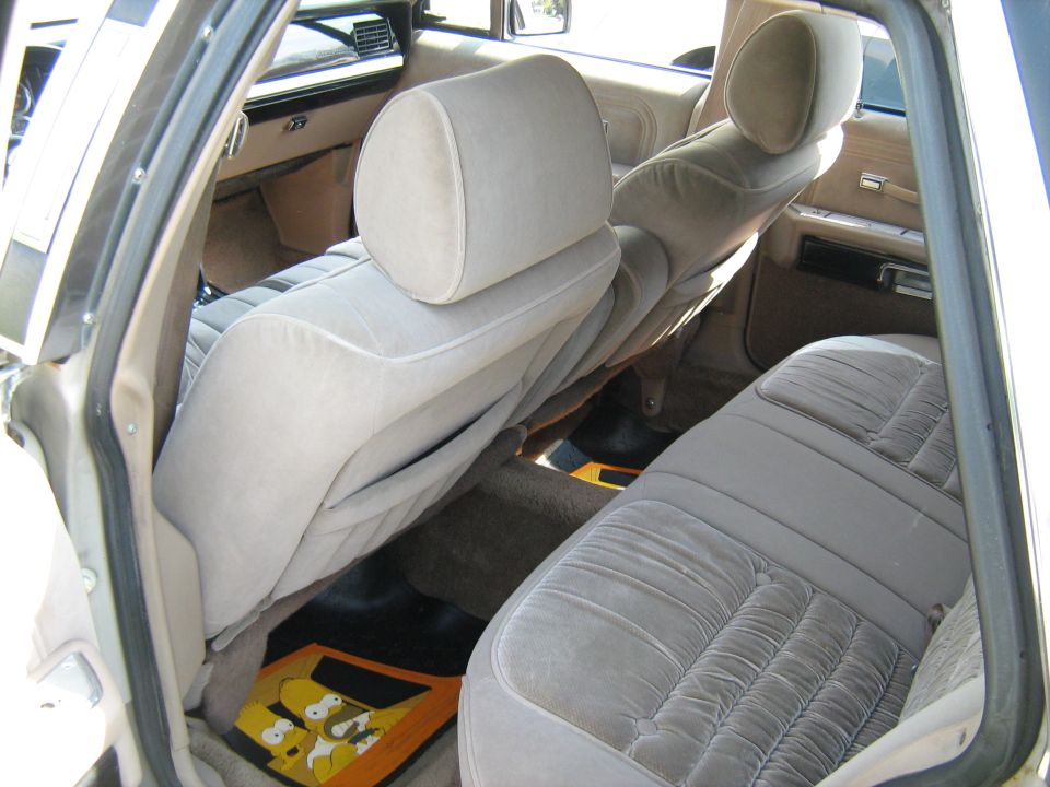 Interior view of a car with beige velour seats and Homer Simpson floor mats