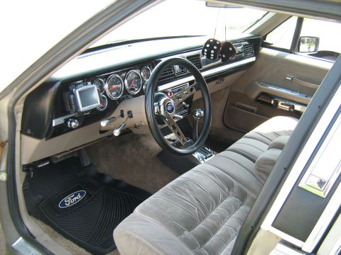 1988 Mercury Grand Marquis - The interior of a car shows velour seats, a custom steering wheel, and a dashboard with multiple gauges.