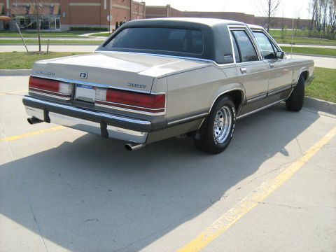 1988 Mercury Grand Marquis - Rear view of a tan 1988 Mercury Grand Marquis, a chrome bumper, dual exhaust pipes, and a black vinyl roof.