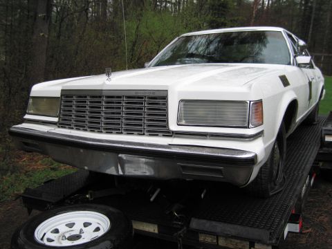 1991 Ford LTD Crown Victoria - Front view of a white sedan with a large chrome grille and 'DODGE' badging, loaded onto a trailer.