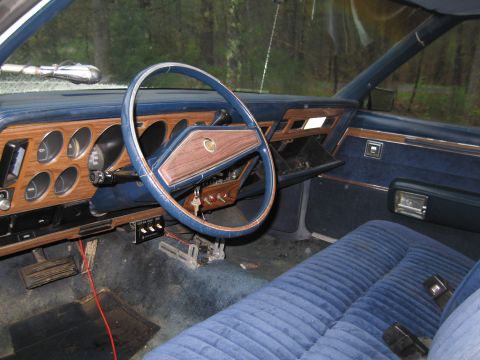 1991 Ford LTD Crown Victoria - The interior of a car with blue velour seats and woodgrain trim on the dashboard is visible.