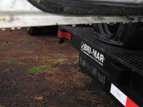 1991 Ford LTD Crown Victoria - A trailer deck is visible with a tire and the 'Bri-Mar Trailers' logo. Water droplets are on the surface above.