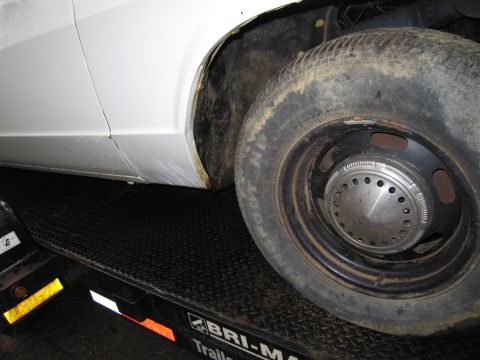 1991 Ford LTD Crown Victoria - Close-up of a white car's fender and wheel, resting on a black trailer.