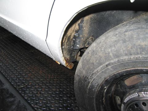 1991 Ford LTD Crown Victoria - Rust is visible on the wheel well of a white vehicle with a worn tire.