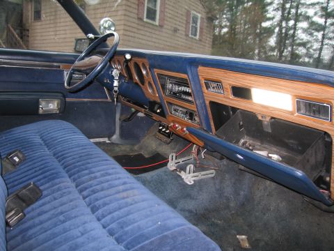 1991 Ford LTD Crown Victoria - The interior of an older vehicle features blue velour seats and a wood-grain dashboard with an open glove box.