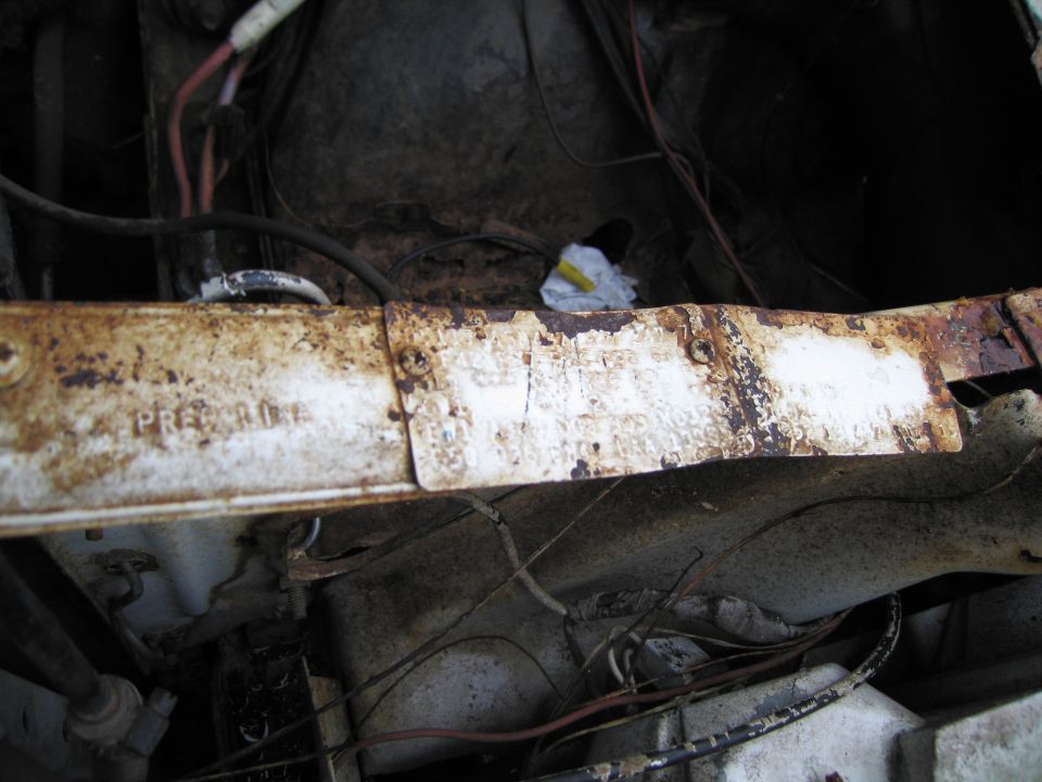Rusty metal beam in engine bay with visible text "PRE-ROD"