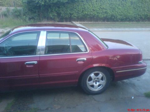 1998 Ford Crown Victoria - Side profile of a red 1998 Ford Crown Victoria sedan with chrome window trim.
