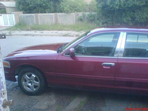 1998 Ford Crown Victoria - The side profile of a maroon sedan is shown, with chrome trim along the windows and door handles.