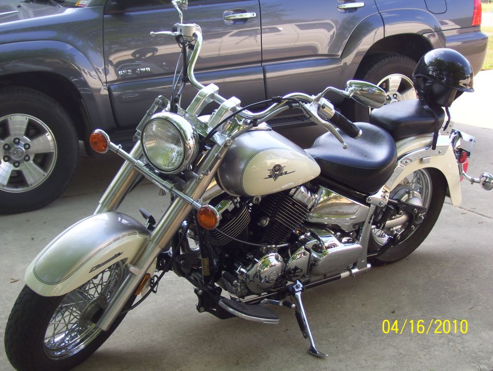 Cream and chrome motorcycle parked next to a dark SUV