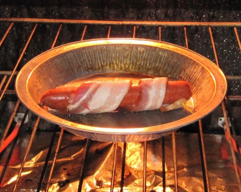 1990 Ford Bronco - Bacon-wrapped hot dog cooking in a foil pan on an oven rack.