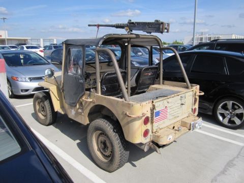 1990 Ford Bronco - This modified jeep, equipped with a heavy machine gun and an American flag decal, is parked in a lot.