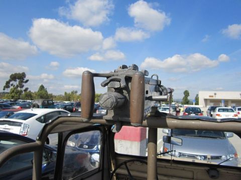 1990 Ford Bronco - A vehicle equipped with a mounted machine gun is parked in a lot with other cars.