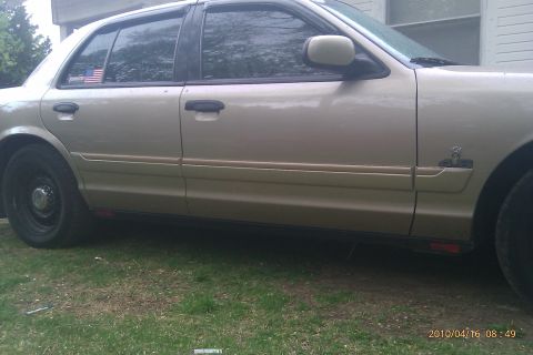 2000 Mercury Grand Marquis - A gold 2000 Mercury Grand Marquis sedan is parked on grass, viewed from the side.