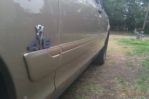 2000 Mercury Grand Marquis - Close-up of a car's side panel showing a 4.6 V8 engine badge and woodgrain trim.
