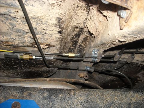 1979 Ford F-150 - Close-up view of brake lines and their fittings underneath a vehicle.