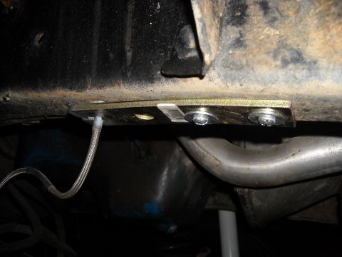 1979 Ford F-150 - A close-up view of the undercarriage shows a newly installed part attached to the frame, with a brake line and exhaust system visible.