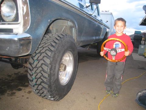 1976 Ford F-250 - A young boy proudly holds a new steering wheel next to a classic Ford F-250 truck.