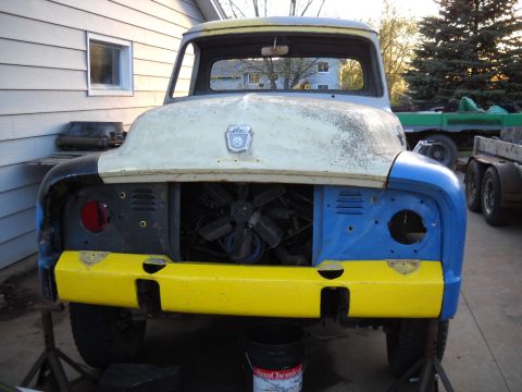 1954 Ford F-100 - A partially disassembled 1953 Ford F-100 truck sits outdoors with its engine visible and mismatched paint on the front.