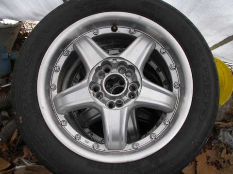 1997 Ford Taurus - A silver 5-spoke two-piece alloy wheel with exposed rim bolts, mounted on a Kumho tire with raised white lettering, laid on the ground outd…
