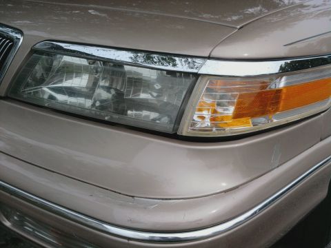 1996 Mercury Grand Marquis - Close-up of a tan sedan's front end, showing the headlight and bumper details.