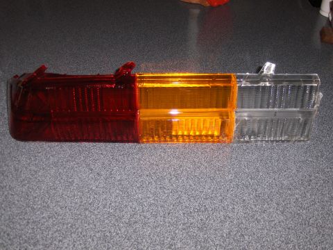 1980 Chevrolet Camaro - A red, amber, and clear tail light assembly is shown against a textured gray surface.