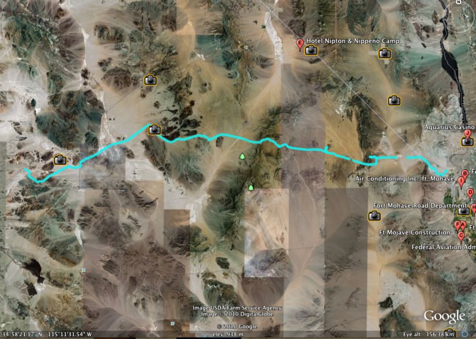 Google Earth map showing a blue route through a desert landscape with camera icons and place markers
