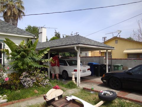 1995 Ford Taurus - A white sedan is parked under a carport, with a black car partially visible to the right.