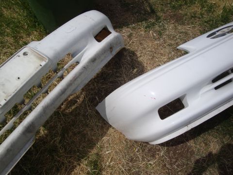 1995 Ford Taurus - Two car bumpers, one white and one unpainted, are displayed on the ground.