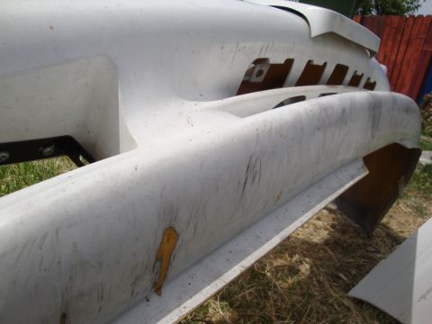 1995 Ford Taurus - Close-up of a damaged white car bumper showing scratches and a yellow paint chip.