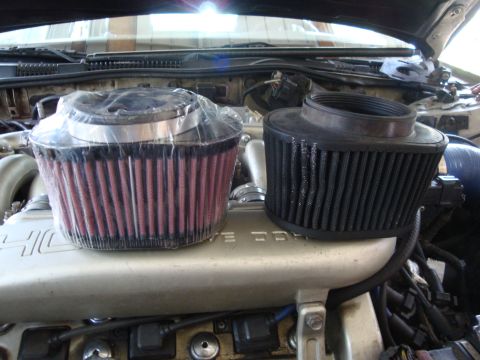 1995 Ford Taurus - Comparison of a new and used engine air filter placed on top of a car engine.