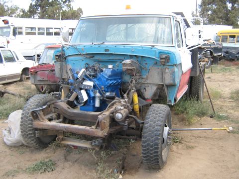 1972 Ford F-250 - This truck is missing its front clip and has a bright blue engine installed. Other vehicles are visible in the background.
