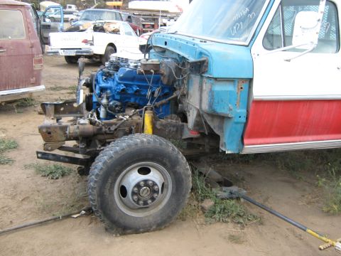 1972 Ford F-250 - A disassembled Ford F-250 truck sits in a junkyard with its engine exposed.