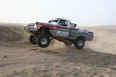 1988 Ford Bronco - Custom off-road truck airborne during a race, showing extensive modifications for off-road performance.