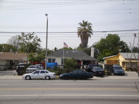 1995 Ford Taurus - A residential street scene with multiple vehicles parked along the curb.