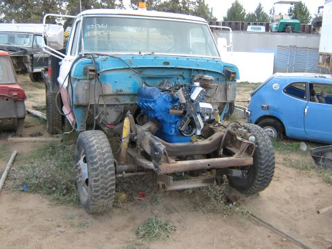 1972 Ford F-250 - Project Ford truck in a dirt salvage yard with its grille, fenders and front sheetmetal removed, exposing a freshly painted blue V8 with a…