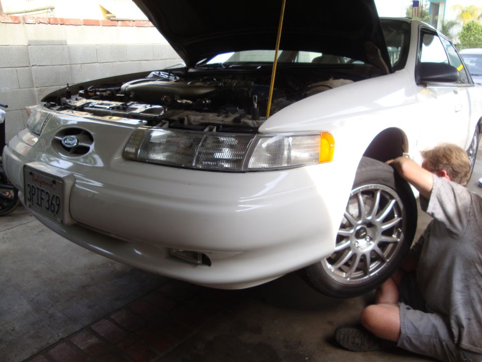 1995 Ford Taurus with hood up, someone working on front wheel