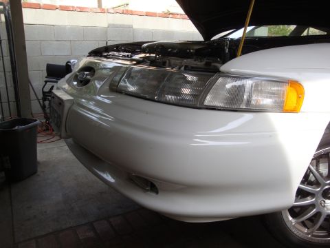 1995 Ford Taurus - The front end of a white 1995 Ford Taurus is visible with the hood open, showing the engine bay.