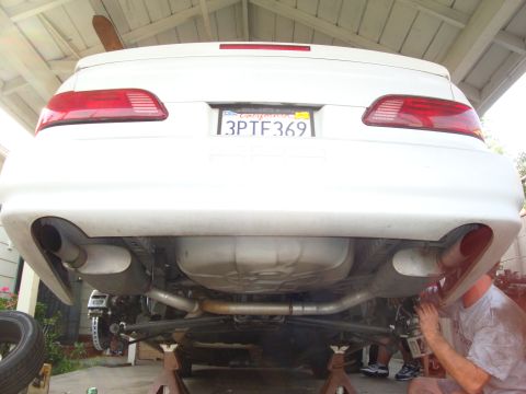 1995 Ford Taurus - The rear of a white 1995 Ford Taurus is shown on jack stands, highlighting its dual exhaust system and California license plate.
