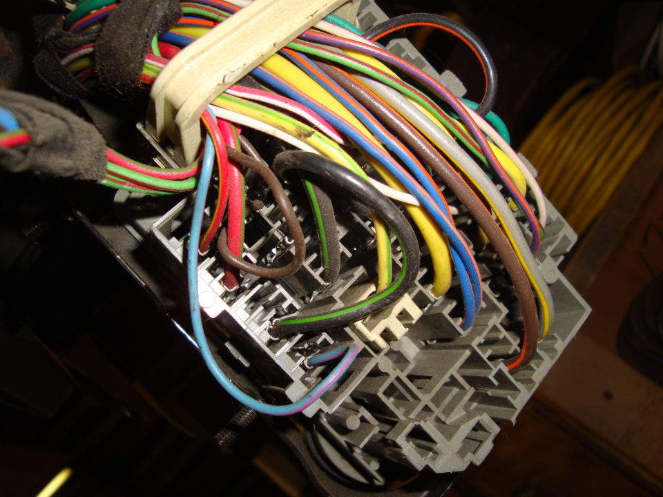 Close-up of a gray automotive wiring harness connector with many colorful wires